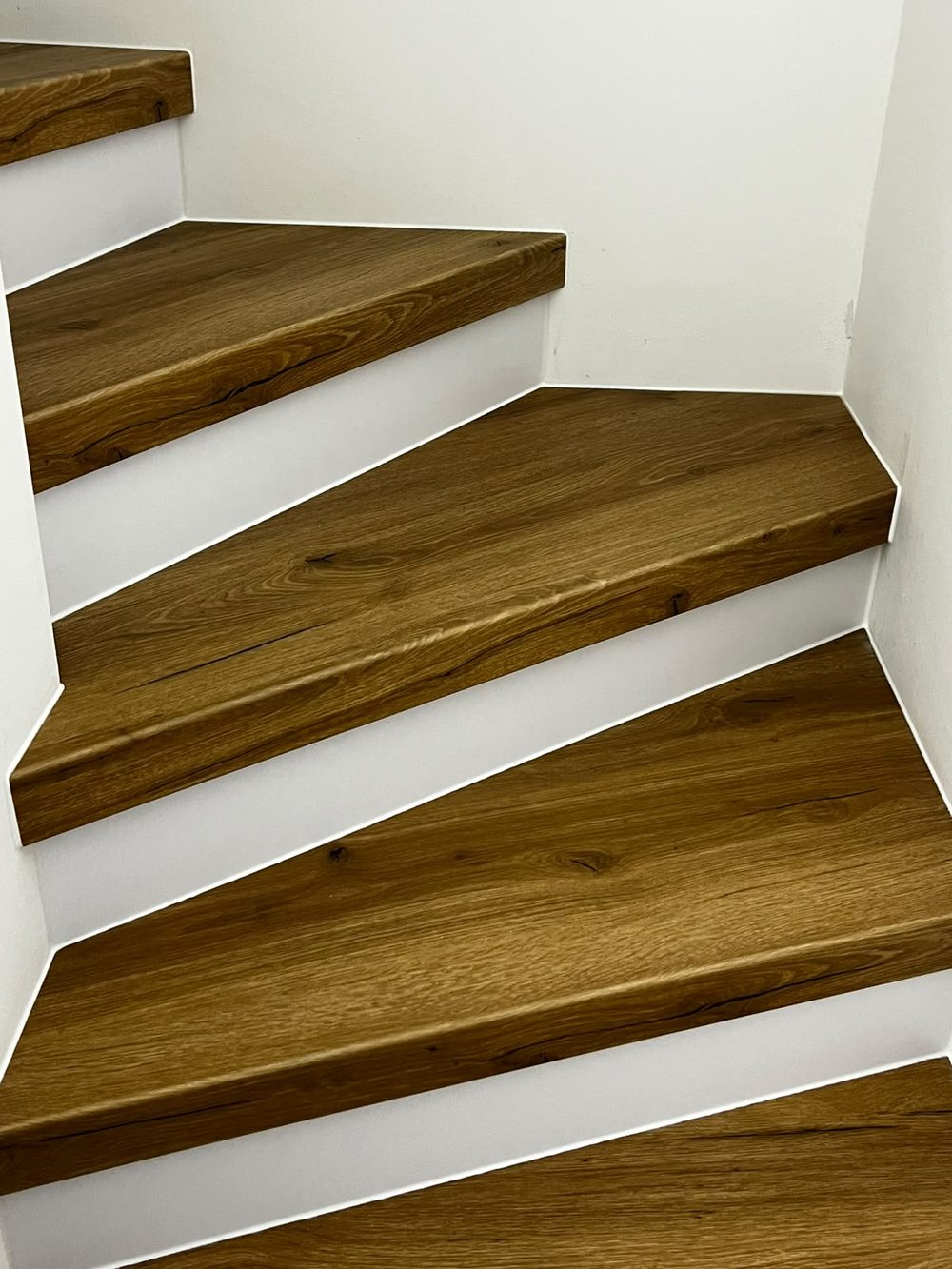 Renovierte Treppe mit dunklem Holzdekor und weißen Stellstufen in einem Wohnhaus