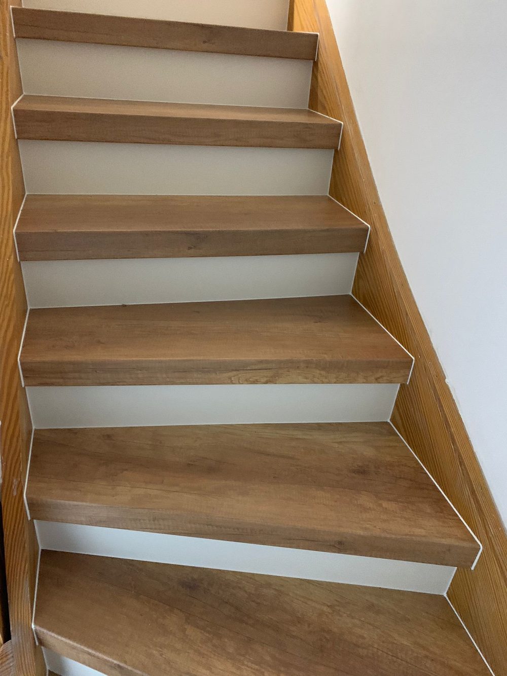 Gerade Treppe mit hellen Holzstufen und weißen Stellstufen