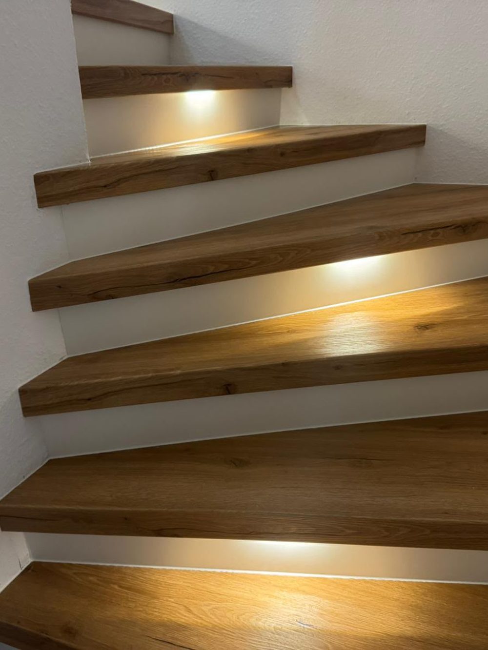 Renovierte Treppe mit warmem Holzdekor und indirekter Stufenbeleuchtung
