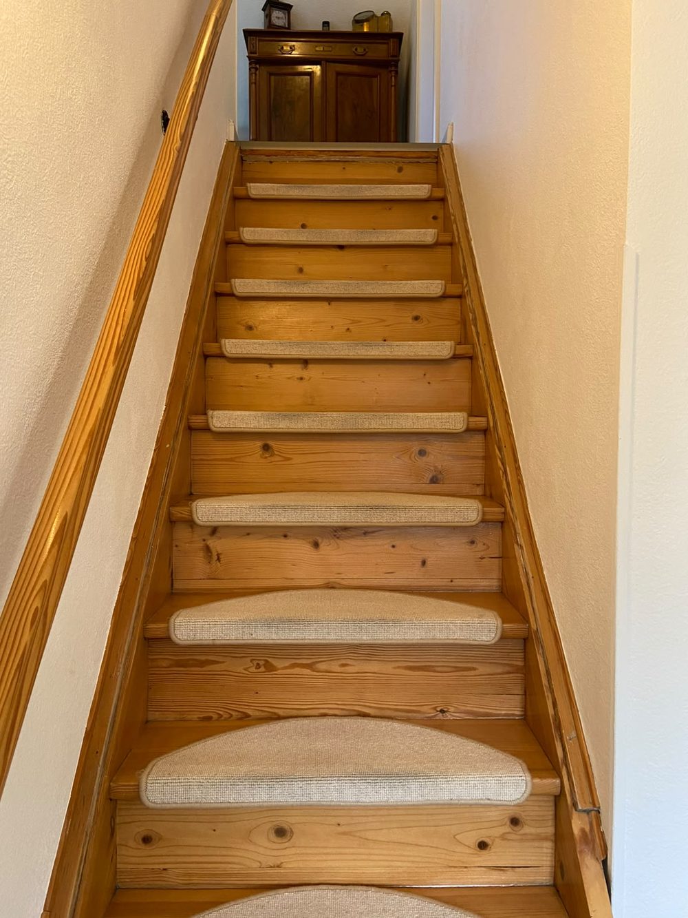 Alte Holztreppe mit aufgeklebten Stufenmatten und vergilbtem Lack