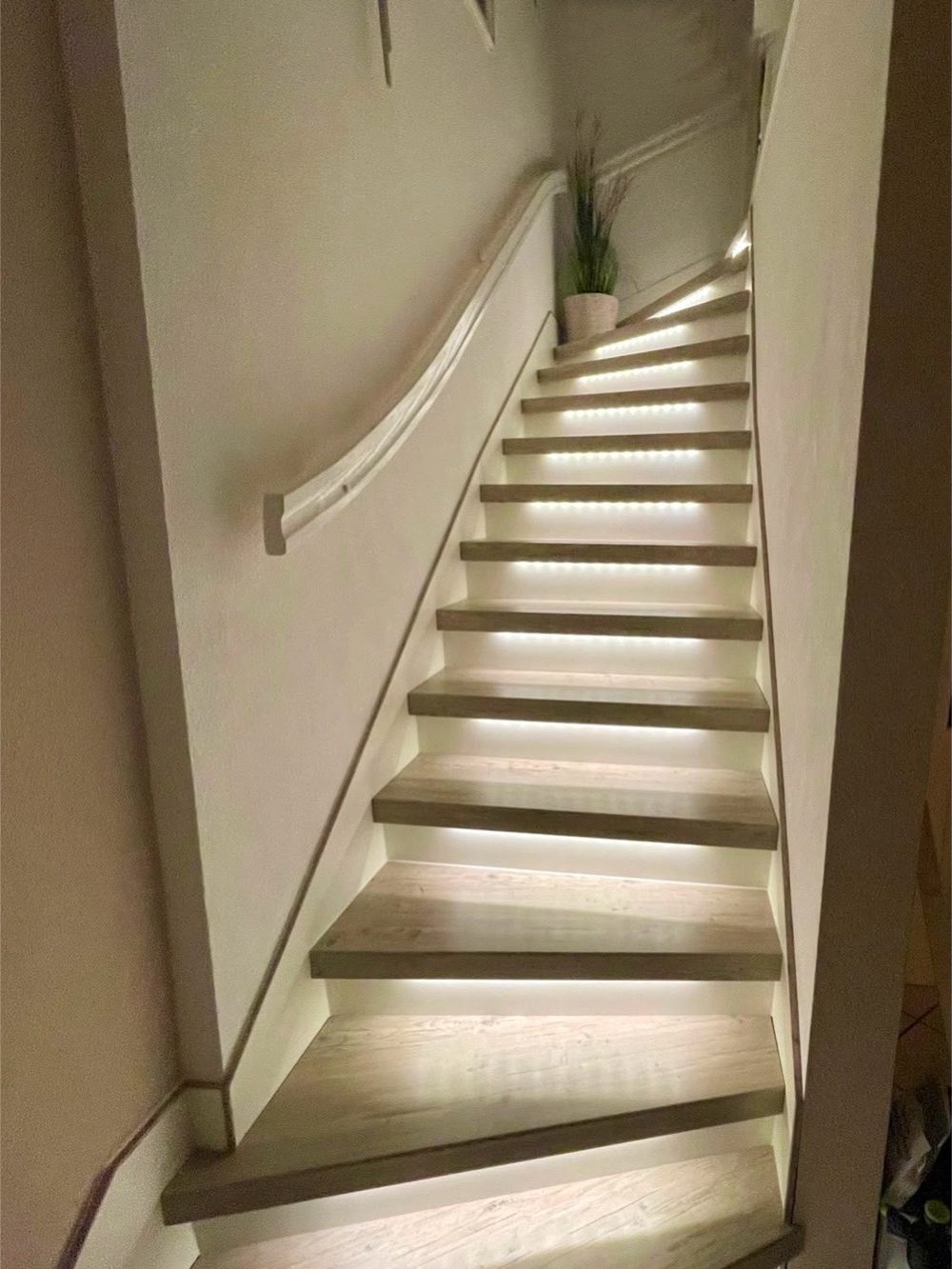 Die gleiche gewendelte Treppe nach der Renovierung mit hellen Stufen ohne Teppich