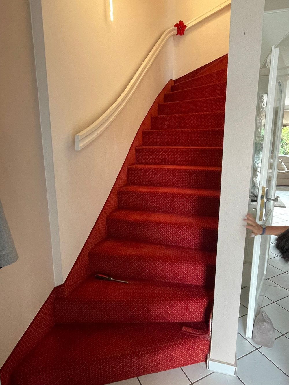 Gewendelte Treppe mit altem rotem Teppichbelag vor der Renovierung