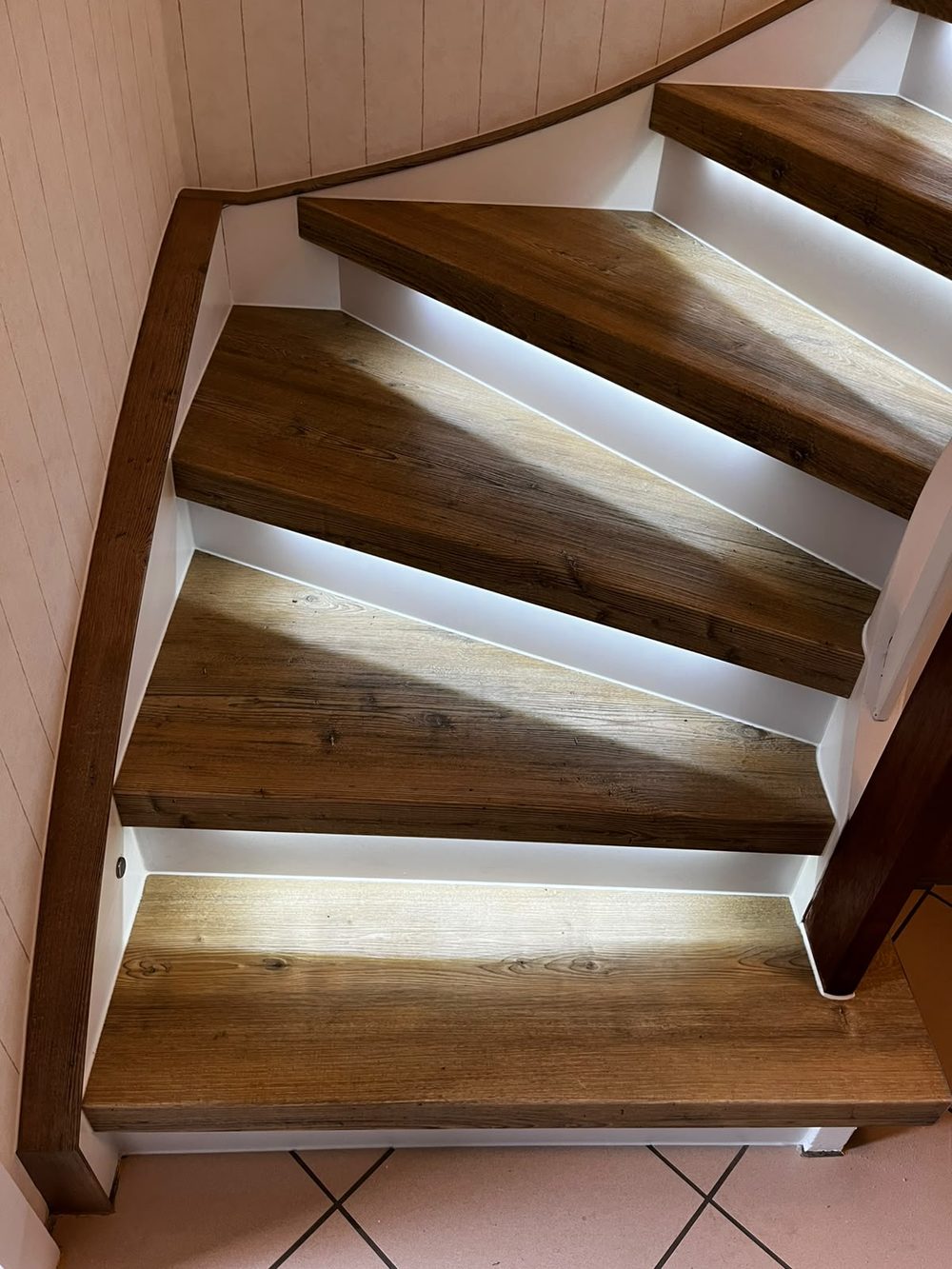 Die renovierte gewendelte Treppe mit hellen Holzstufen und weißen Stellstufen