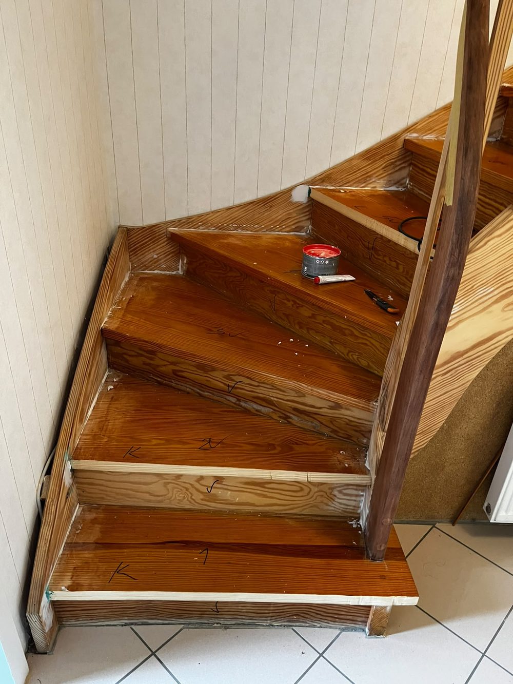 Alte, dunkel lackierte gewendelte Holztreppe mit sichtbaren Gebrauchsspuren