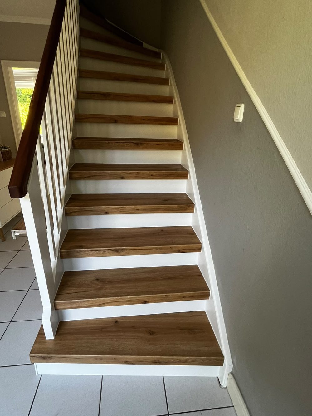 Die renovierte Treppe mit warmen Holzstufen und weiß abgesetzten Stellstufen