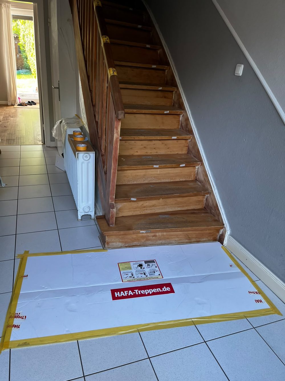 Alte, dunkle Holztreppe mit ausgetretenen Stufen, davor eine Schutzmatte für die Montage