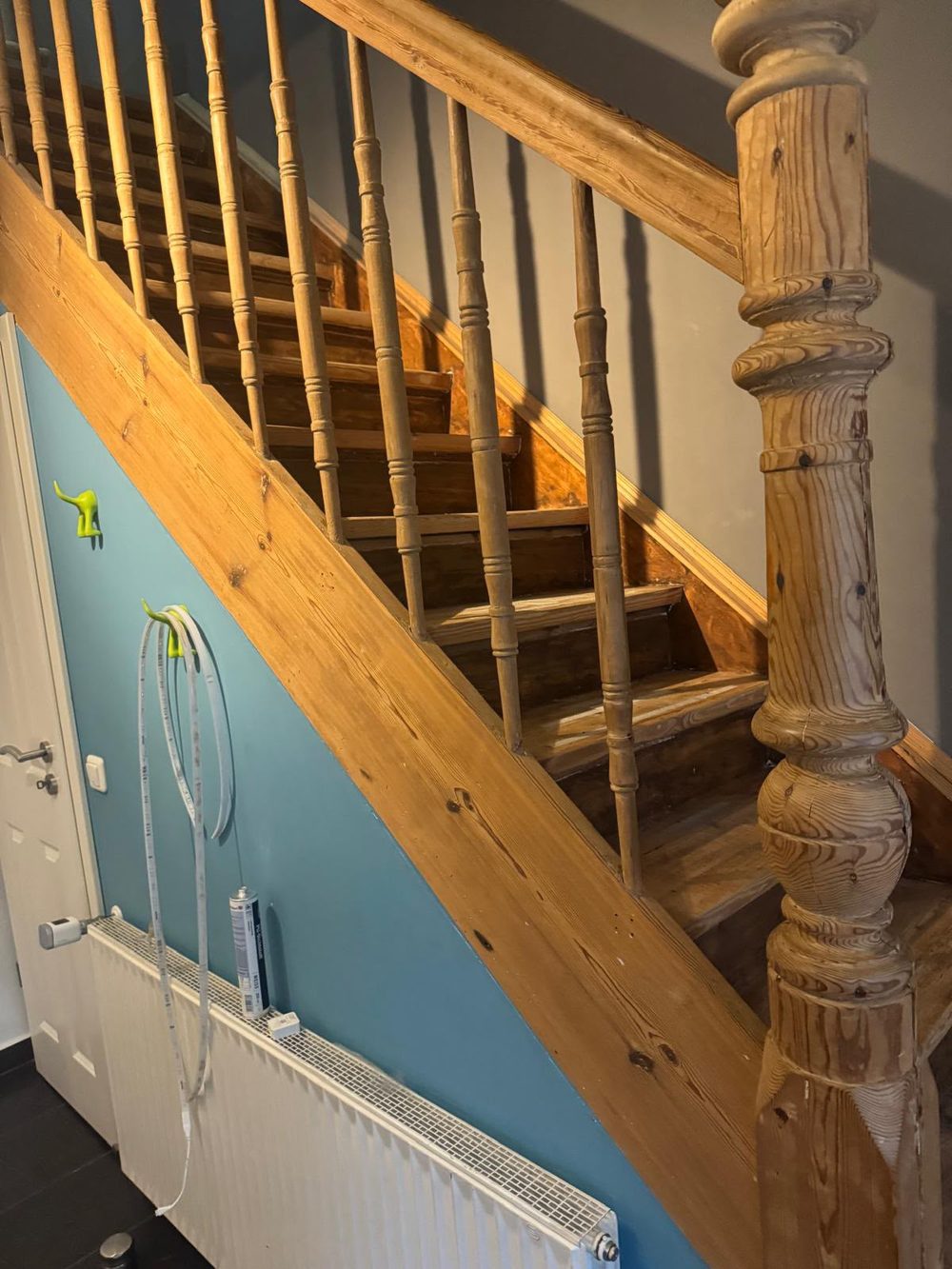 Alte Kiefernholztreppe mit gedrechselten Geländerstäben vor blauer Wand