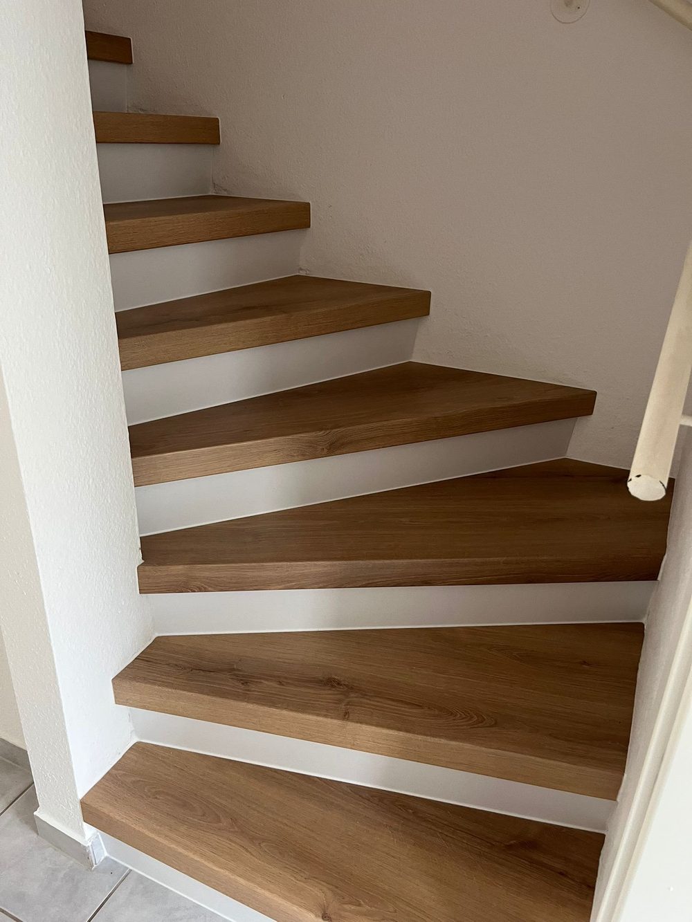 Die renovierte Wendeltreppe mit neuen Holzstufen und weißen Stellstufen