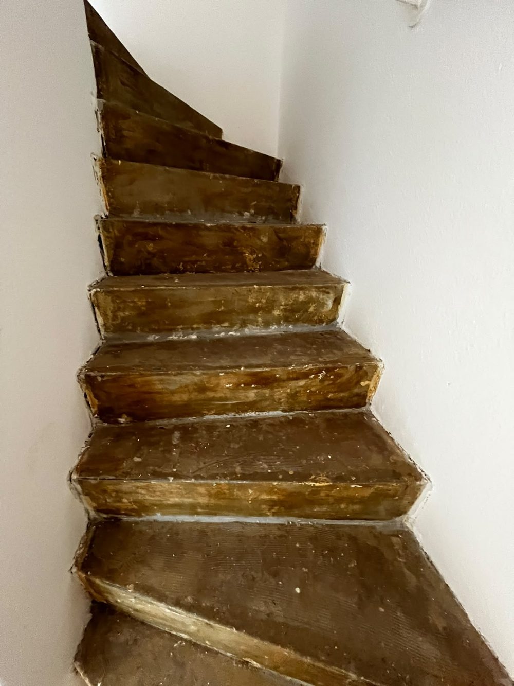 Stark abgenutzte, gelblich vergilbte Holztreppe mit ausgetretenen Trittflächen