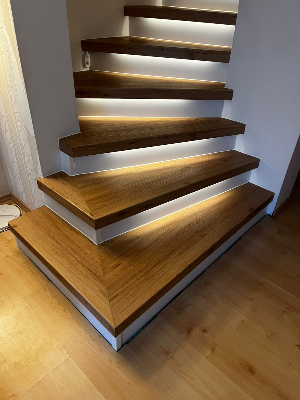 Dieselbe Betontreppe nach der Renovierung mit Holzstufen und indirekter LED-Stufenbeleuchtung