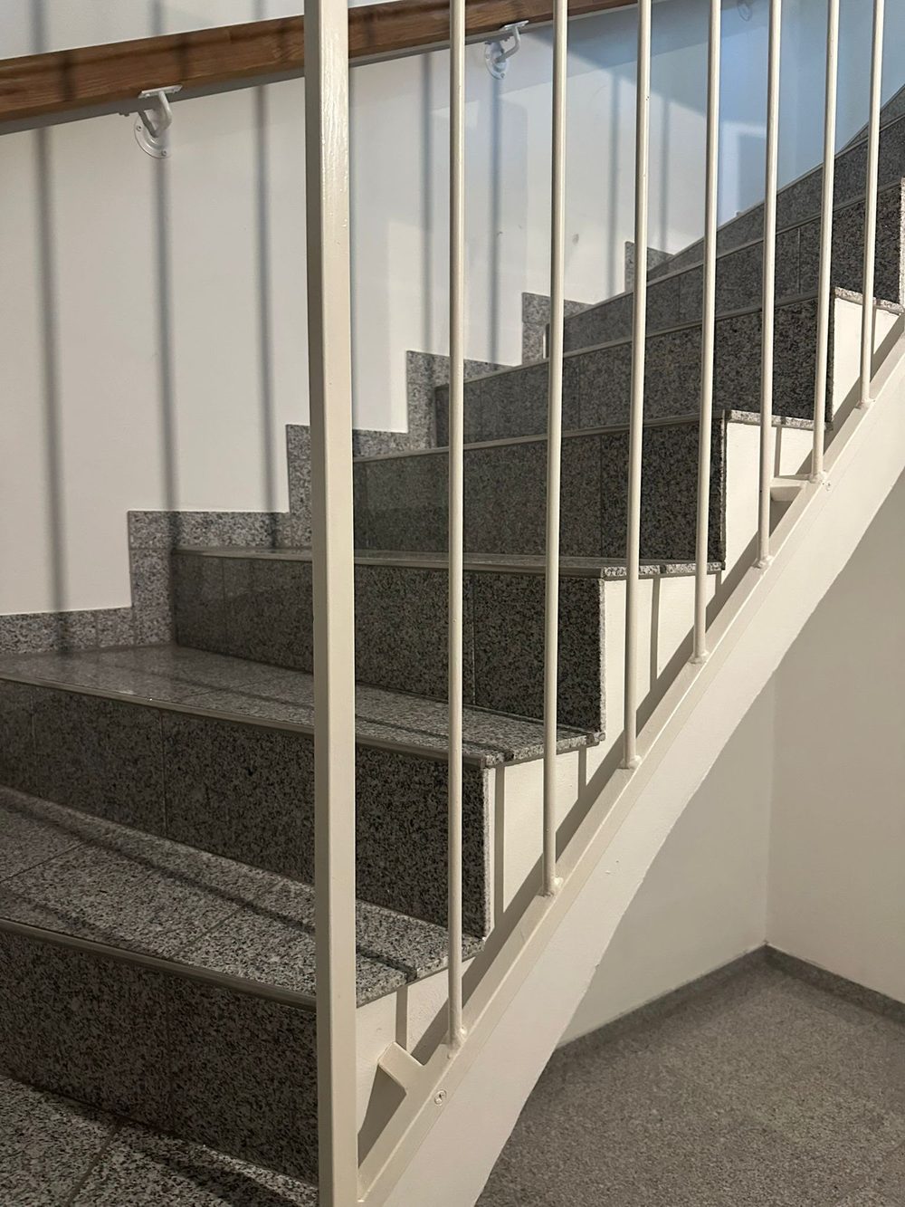 Alte Terrazzo-Steintreppe mit weißem Metallgeländer vor der Renovierung